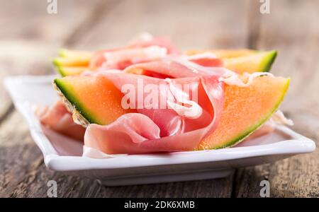 melone con prosciutto su tavola di legno Foto Stock