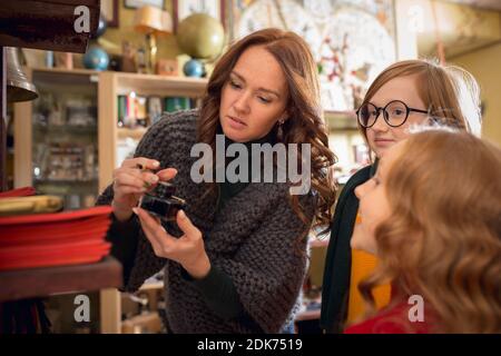 Inkwell. Famiglia allegra, madre e bambini in cerca di decorazione domestica e regali di festa nel negozio di famiglia. Eleganti oggetti retrò per saluti o design. Ristrutturazione degli interni, festeggiando il tempo. Foto Stock