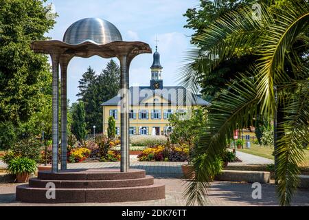 Germania, Baden-Wuerttemberg, Bad Rappenau. Monotteros all'ingresso del giardino delle saline con l'edificio degli uffici delle saline Foto Stock