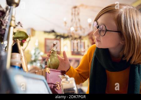 Giocattoli. Allegro piccolo ragazzo biondo in cerca di decorazione domestica e regali di festa nel negozio di famiglia. Eleganti oggetti retrò per saluti o design. Ristrutturazione degli interni, festeggiando il tempo. Foto Stock