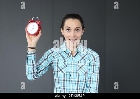 La donna sorpresa tiene in mano la sveglia rossa Foto Stock