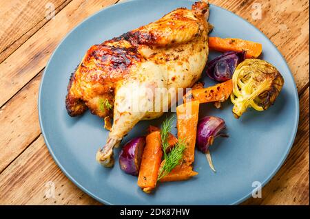 Gustosi pezzi di pernice fritti con zucca. Pollo arrosto con verdure su un tavolo di legno Foto Stock