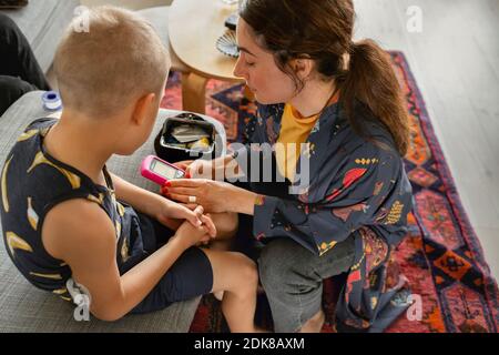 Mother checking sons insulin pump Stock Photo