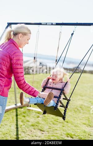 Mother swinging daughter Stock Photo