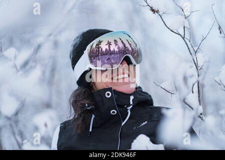 Donna sorridente indossando occhiali da sci Foto Stock