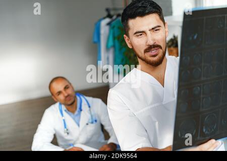 Due medici di sesso maschile esaminano la risonanza magnetica cerebrale di un paziente nel cabinet Foto Stock