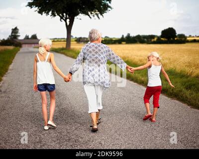 Nonna mano in mano con i nipoti in campagna Foto Stock