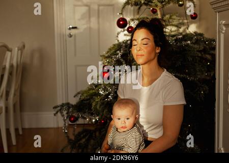 Madre con il bambino davanti all'albero di Natale Foto Stock