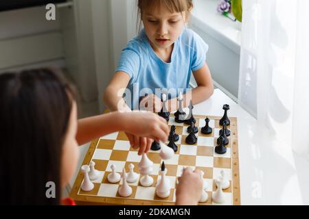 Due graziosi bambini che giocano a scacchi a casa Foto Stock