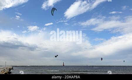Un kite-boarder windsurf in una giornata parzialmente nuvolosa con un faro sullo sfondo Foto Stock