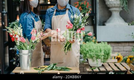 Fioristi maschili e femminili si sono concentrati sulla composizione in fioreria Foto Stock