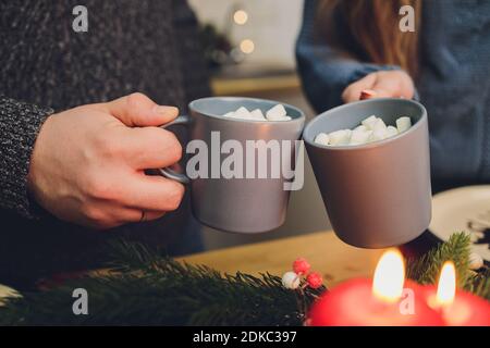 Due bicchieri di cacao fatti in casa con marshmallows. Bevanda calda invernale su sfondo di legno decorata con bastoni di cinamon e rami di abete Foto Stock