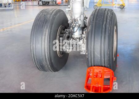 Carrello di atterraggio aereo in primo piano in gomma telaio hangar, ruota supportata da un pattino rosso freno Foto Stock