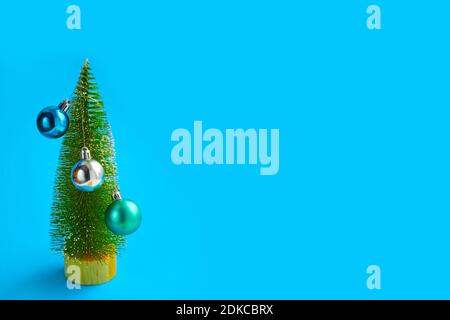 albero di natale con piccole decorazioni su sfondo blu, sfondo astratto, concetto di natale minimalista. Foto Stock
