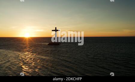 Croce cattolica nel cimitero affondata nel mare al tramonto, antenna fuco. colorato cielo durante il tramonto. Grandi crucafix segnando il sottomarino sunken cimitero, CAMIGUIN ISLAND Filippine. Foto Stock