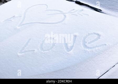 immagine di un cuore rotto con una freccia nel neve sul cofano di un'auto su una gelata giorno invernale Foto Stock