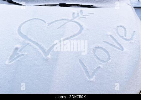 immagine di un cuore rotto con una freccia nel neve sul cofano di un'auto su una gelata giorno invernale Foto Stock