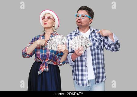 Paio di certi amici, adulto uomo e donna casual in camicia a scacchi in piedi insieme mantenendo la ventola di dollari e le dita di puntamento a se stesso w Foto Stock