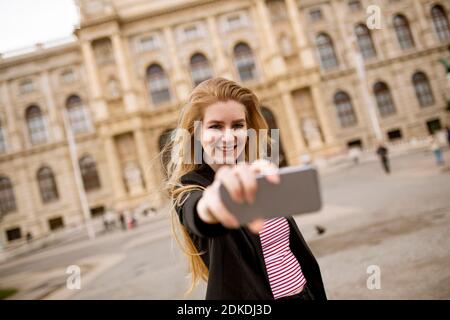 Giovane donna turistica scattando selfie con foto mobile sulla strada nel centro di Vienna, Austria Foto Stock