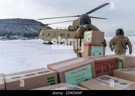 I guardie nazionali scaricano i regali di Natale da un elicottero CH-47 Chinook al remoto villaggio isolato di Alutiq come parte dell'operazione Babbo Natale 11 dicembre 2020 a Nanwalek, Alaska. Operazione Babbo Natale è un programma annuale di attività della comunità che fornisce regali di Natale, libri, forniture scolastiche e stuffer di stoccaggio per i bambini nelle comunità rurali dell'Alaska. Foto Stock