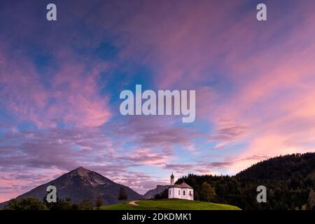 Il piccolo Annakircherl, una piccola cappella su una collina in Achenkirch sul Rend des Karwendel nelle Alpi, Tirolo dopo il tramonto. I toni viola e blu dominano il cielo serale. Sullo sfondo le montagne. Foto Stock