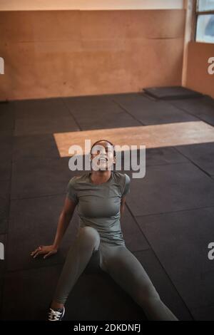 Fit young African American woman in sportswear sitting on a gym floor and sweating after a workout Stock Photo