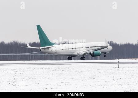 L'aereo decolta dalla pista innevata dell'aeroporto in caso di maltempo durante una tempesta di neve, un forte vento in inverno Foto Stock