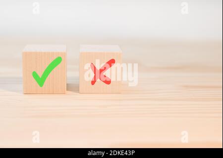 Segno di spunta e segno di croce x su cubi di legno. Blocchi di legno con segno di spunta verde e rosso x. Concetto di presa di decisione positiva o negativa o di scelta o. Foto Stock