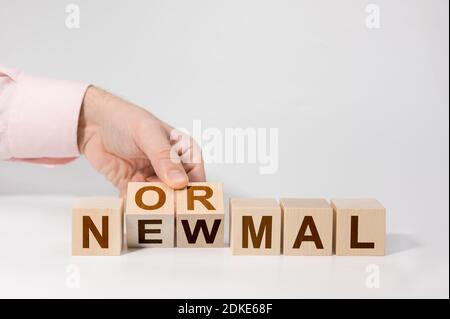 Flipping mano cubetti di legno con nuova parola NORMALE. Adattamento a nuova vita o post-blocco aziendale dopo la pandemia del coronavirus. Affari con la dista sociale Foto Stock