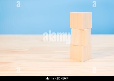 tre cubi di legno per il tuo testo, icone, segni e simboli per creare i tuoi concetti creativi. Fock su cubi di legno vergini. Blocchi su tavola di legno, bac blu Foto Stock