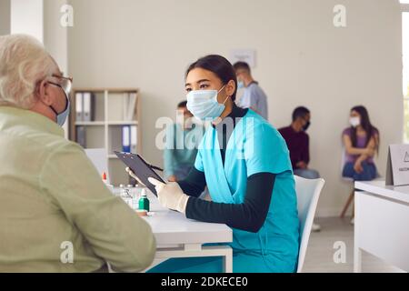Nurse informs an older man about the benefits and possible side effects of the vaccine. Foto Stock
