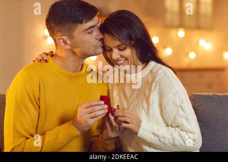 L'uomo bacia una donna sulla fronte mostrandogli un anello di nozze dopo una proposta di matrimonio riuscita. Foto Stock