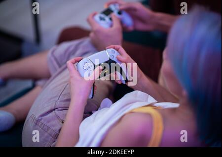 Accoppia a casa tua con PlayStation 5 e diverse generazioni di joystick per console: Controller DualSense per PS5 e gamepad DualShock per PS4 in una mano Foto Stock