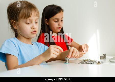 ritratto di bambine che siedono al tavolo e calcolano i soldi Foto Stock