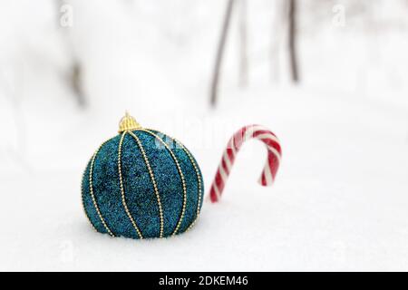 Palla giocattolo di Natale con canna caramella sulla neve. Sfondo invernale per la celebrazione di Capodanno, biglietto d'auguri Foto Stock