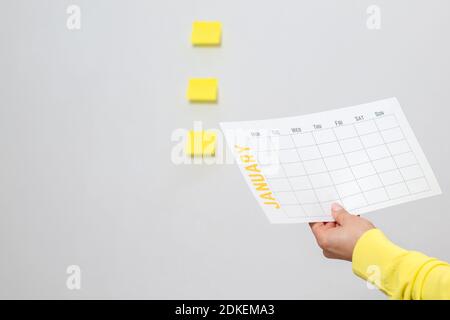 La mano di una donna ha un nuovo calendario per gennaio. Pianificazione del nuovo anno, obiettivi, azioni, strategie, soluzioni, successo aziendale. Concetto minimo.Copia Foto Stock