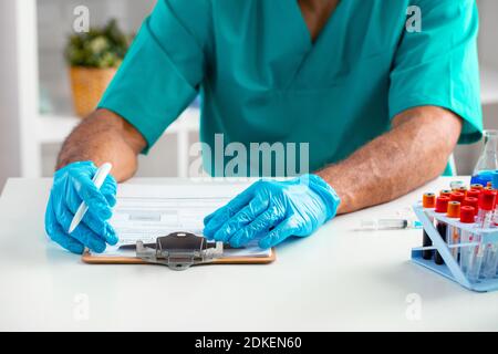 Primo piano delle mani del medico che prende appunti sul tavolo Foto Stock