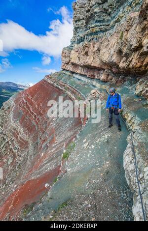 Giovane uomo di 22 anni lungo il percorso attrezzato Astaldi (caratteristico per le rocce colorate) ai piedi di Tofane, Cortina d'Ampezzo, Dolomiti, Belluno, Veneto, Italia Foto Stock