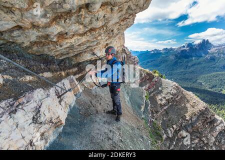 Giovane uomo di 22 anni lungo il percorso attrezzato Astaldi (caratteristico per le rocce colorate) ai piedi di Tofane, Cortina d'Ampezzo, Dolomiti, Belluno, Veneto, Italia Foto Stock