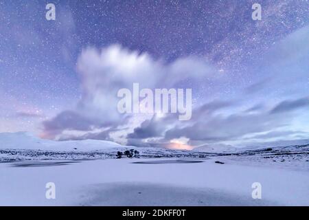 Tempesta di neve che si avvicina su neve e congelato Loch awe, Scozia all'alba Foto Stock