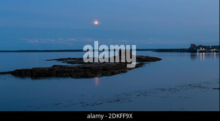 Vecchia, decadente capanna di tronchi (vecchio fienile) su un piccolo fienile disertato isolano su una nuvolosa, nanna luna piena sera tardi, Mar Bianco, Russia Foto Stock