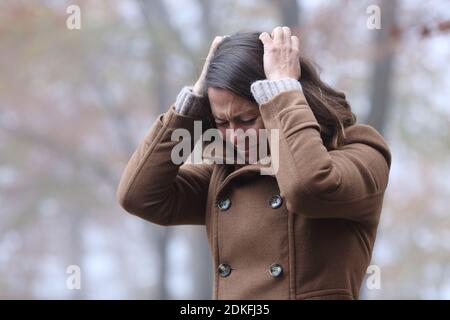 Donna disperata che lamenta da sola afferrare i capelli con le mani in un parcheggia in inverno Foto Stock