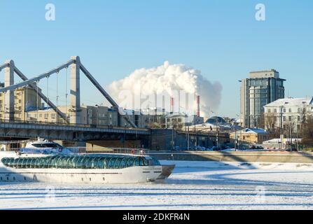 Mosca, Russia - 8 Gennaio 2017: il piacere in barca a vela su un fiume congelato sotto il ponte di strutture metalliche, gelido inverno pieno di sole giorno sullo sfondo Foto Stock