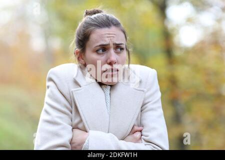 Donna arrabbiata che si fa freddo lamentando camminare in inverno in un parcheggio Foto Stock