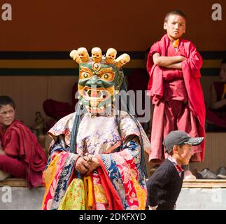 Lamayuru, India - 17 giugno 2012: Il monaco esegue una danza religiosa mascherata e in costume del buddismo tibetano e dei monaci bambini che guardano con attenzione Foto Stock