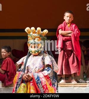 Lamayuru, India - 17 giugno 2012: Il monaco esegue una danza religiosa mascherata e in costume del buddismo tibetano e dei monaci bambini che guardano con attenzione Foto Stock