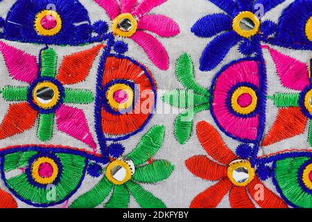 Colorato ricamo Kutchi su tela tessitura dont da artigiani. Lavori di filo fatti a mano, lavoro di specchio da Gujarat, India Foto Stock
