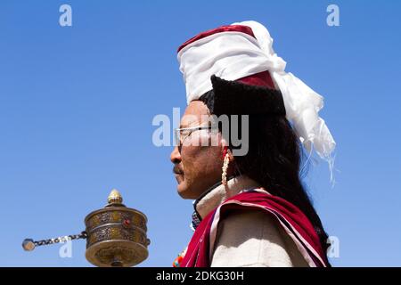 Leh, Jammu e Kashmir, India - Set 01, 2012: L'uomo Ladakhi con ruota di preghiera a mano in Abbigliamento tradizionale con il cappello familiare che si trova solo Foto Stock