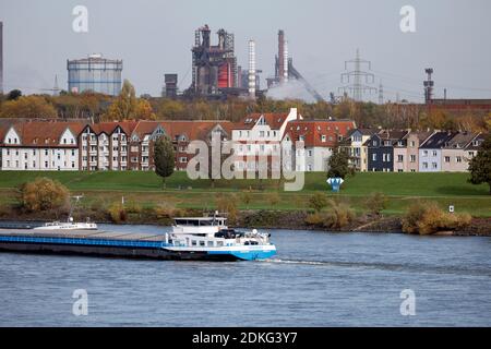 Duisburg, Renania Settentrionale-Vestfalia, Germania - paesaggio urbano nella zona della Ruhr con le navi della navigazione interna sul Reno di fronte agli edifici residenziali nel distretto di Laar e sul retro l'altoforno 8 da ThyssenKrupp Huettenwerk a Brukhausen Foto Stock