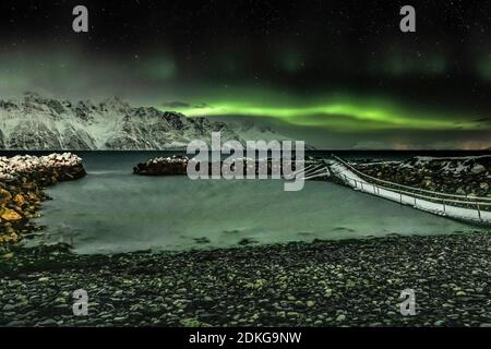 Northern lights on the wintry Lyngenfjord with snow-capped mountains in the background Stock Photo